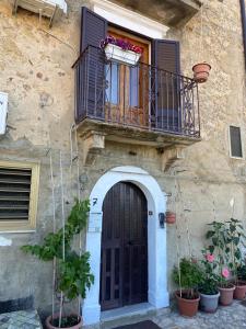 ein Gebäude mit einer Tür und einem Balkon mit Topfpflanzen in der Unterkunft casa sulla roccia in Sperlinga