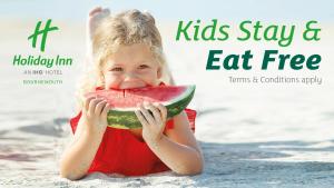 a little girl is eating a slice of watermelon at Holiday Inn Bournemouth by IHG in Bournemouth