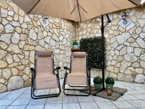 two chairs and an umbrella in front of a stone wall at AMATI HOLIDAYS in Palermo +5 photos