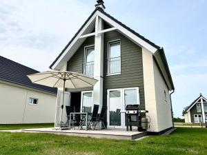 a small house with a table and an umbrella at Ferienhaus Fischkopf mit Sauna und Strandkorb in Büsum