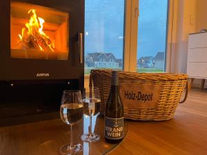 a bottle of wine and two glasses on a table with a fireplace at Ferienhaus Fischkopf in Büsum