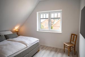 a bedroom with a bed and a chair and a window at Moin Ahoi Reethaus in Fehmarn