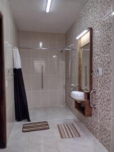 ein Bad mit einer Dusche und einem Waschbecken in der Unterkunft Jardins de Canela - Aptos e Casas Bairro Nobre em Canela in Canela