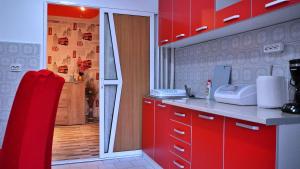 a kitchen with red cabinets and a sliding glass door at Apartament Deny in Sulina