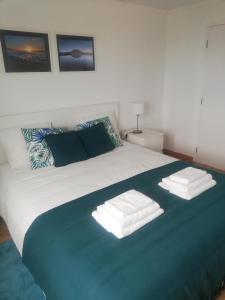 a white bed with two folded towels on it at Vitamin Sea in São Roque do Pico