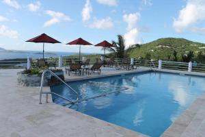 a swimming pool with chairs and umbrellas on a resort at Serene Cruz Bay Villa Sep Mstr Kg Suite Stunning Sunsets in Cruz Bay +8 photos