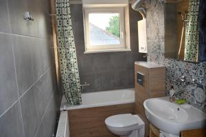 a bathroom with a sink and a toilet and a window at Przytulne duże mieszkanie w domku jednorodzinnym in Koszalin