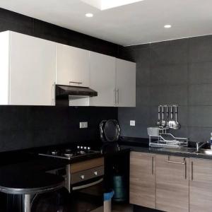 a kitchen with black and white cabinets and a stove at Studio Tamourit Taghazout Bay à 300 m de la plage in Taghazout