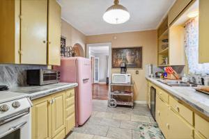 uma cozinha com um frigorífico cor-de-rosa e um lavatório em The Old Downtown Historic Grand Prairie House home em Grand Prairie