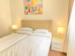 a bedroom with a white bed with two lamps at Steiner Residences Vienna Augarten in Vienna