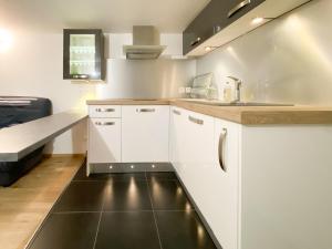 a kitchen with white cabinets and a black floor at LE PETIT RAMBOLITAIN in Rambouillet