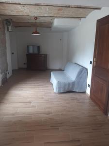 um quarto com uma cadeira branca num quarto com piso em madeira em cascina carlo em Aie