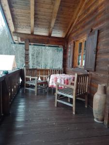 eine Veranda einer Holzhütte mit einem Tisch und Stühlen in der Unterkunft Hüttenzauber Ferienwohnung mitten im Nationalpark in Lindberg