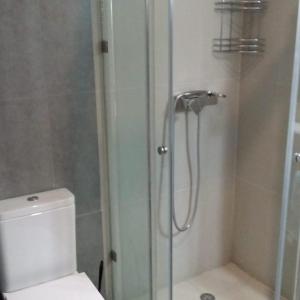 een badkamer met een douche, een toilet en een glazen deur bij Studio Tamourit Taghazout Bay à 300 m de la plage in Taghazout