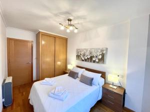 a bedroom with a white bed with two towels on it at Apartamento vistas al mar in Viveiro