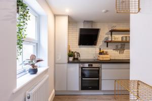 a kitchen with white cabinets and a tv at The Servant’s Quarters in Whitby