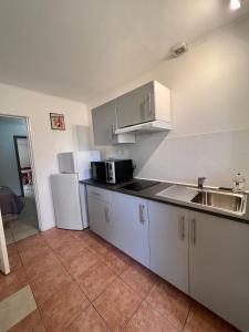 塞里尼昂的住宿－Résidence les Caraibes，厨房配有白色橱柜、水槽和冰箱。