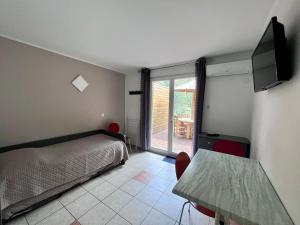 een slaapkamer met een bed en een televisie en een tafel bij Résidence les Caraibes in Sérignan