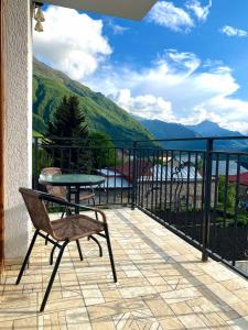 a patio with a table and a chair on a balcony at Mood Hotel Kazbegi in Stepantsminda