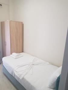uma cama branca num quarto com uma porta de madeira em KORONI MARE APARTMENTS em Koroni