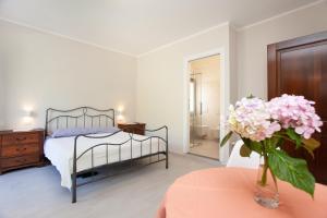 1 dormitorio con 1 cama y un jarrón de flores sobre una mesa en B&B Lu Lioni, en San Teodoro