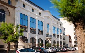 un gran edificio blanco con coches aparcados en un aparcamiento en Lagrange Vacances Les Patios Eugénie en Biarritz