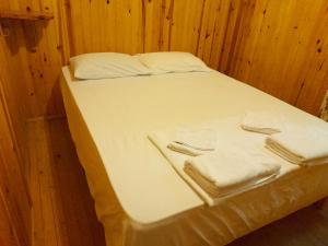 a bed with white sheets and towels on it at Endemik Bungalov in Edremit