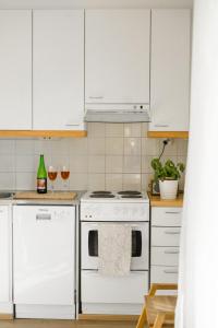 una cocina con armarios blancos y un horno de fogón blanco en Lillmåsen Naantali - atmospheric and very comfy studio, en Naantali