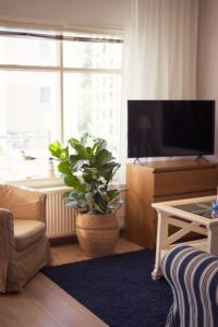 a living room with a television and a potted plant at Lillmåsen Naantali - atmospheric and very comfy studio in Naantali