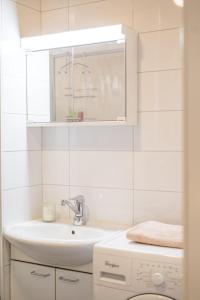 a white bathroom with a sink and a mirror at Lillmåsen Naantali - atmospheric and very comfy studio in Naantali