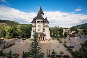 a building with a clock tower with a christmas tree in front at Apartament Style Gura Humorului in Gura Humorului