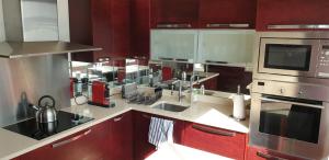 una cocina con electrodomésticos de acero inoxidable y armarios rojos en Appartement Lumineux de 90 m2 situé en centre ville, en Annecy
