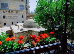 een tuin met rode bloemen voor een gebouw bij Royal Antique Boutique Hotel in Baku