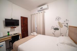 a bedroom with a bed and a desk and a television at Pousada Nativa Jeri in Jericoacoara