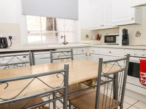 ラムズゲートにあるSandsviewの白いキャビネットと木製テーブル付きのキッチン