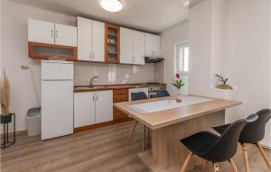 une cuisine avec des placards blancs et une table et des chaises en bois dans l'établissement Stunning Apartment In Nevidane With Wifi, à Neviđane