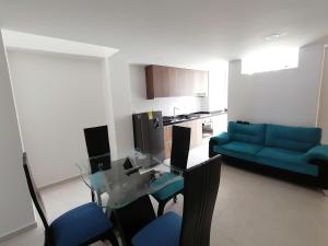a living room with a glass table and a blue couch at Hermoso apartamento nuevo con estacionamiento gratuito in San Gil