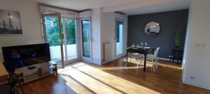 a living room with a dining room table and a television at Design 3 bedrooms appartment, near Champs Elysees in Nanterre