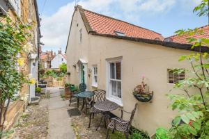 a patio with tables and chairs outside of a building at Brincliffe Cottage in Robin Hood's Bay