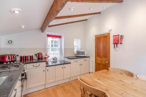 cocina con armarios blancos y mesa de madera en Brincliffe Cottage en Robin Hood's Bay
