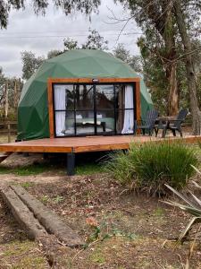 ein grünes Zelt mit einem Tisch und einer Bank in der Unterkunft Don Aniceto Lodges & Glamping in Luján