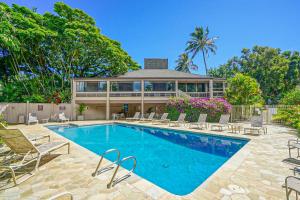 a swimming pool with chairs and a house at Pali Ke Kua 144 in Princeville
