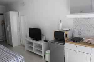 a kitchen with white cabinets and a tv on a counter at Apartments Estelle in Pula