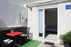 a patio with a red table and chairs and a sliding glass door at Apartments Estelle in Pula
