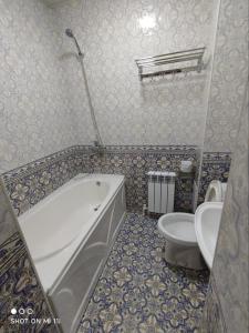 ein Bad mit einer Badewanne und einem WC. in der Unterkunft Oybinokh hotel in Buxoro