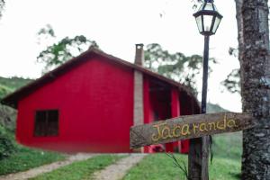 un fienile rosso con un cartello davanti di Sítio das Hortênsias Chalés a Conceição da Ibitipoca