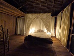 Cama grande en habitación con cortinas en Enchanting Jungle Villa — UMARI, en Iquitos