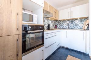 a kitchen with white cabinets and a microwave at Very Bright Cocoon With Balcony Near The Slopes in Courchevel