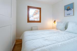 Cama blanca en habitación con ventana en Very Bright Cocoon With Balcony Near The Slopes, en Courchevel