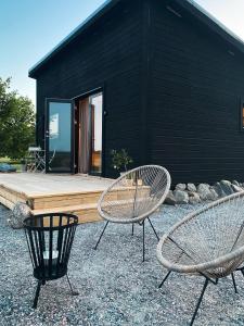 two chairs and a table in front of a house at Field View Cabin in Örebro